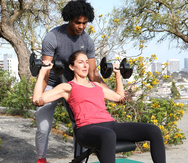 Personal trainer assisting a woman with outdoor strength training